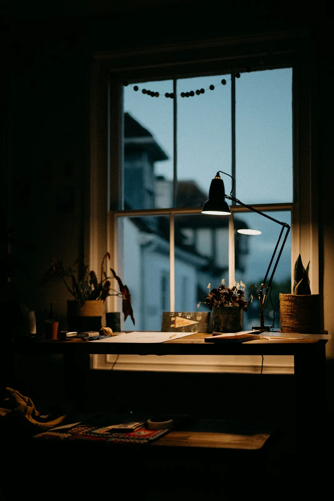 An uncropped portrait photograph of a desk lamp and window.